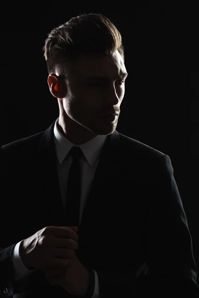 Handsome young man in suit on dark background — Stock Photo, Image