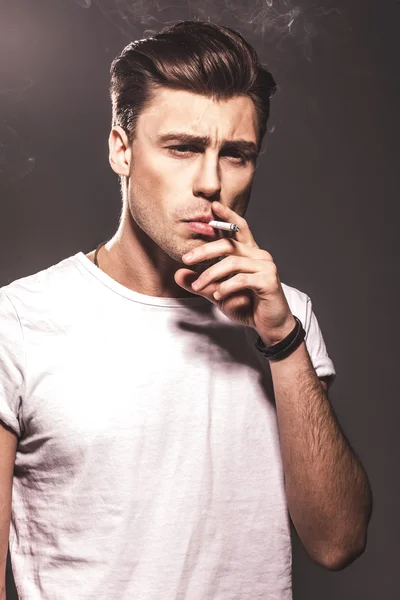 Handsome young man smoking cigarette — Stock Photo, Image