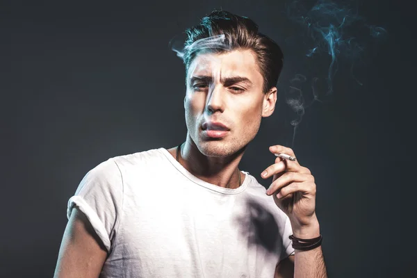 Handsome young man smoking cigarette — Stock Photo, Image