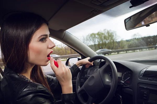 Painted woman lipstick while driving — Stock Photo, Image