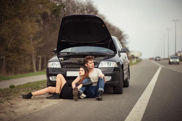 Pareja cerca de un coche roto en el borde de la carretera —  Fotos de Stock