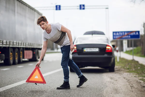 Auto met uitsplitsing langs de weg, man ingesteld waarschuwingsdriehoek — Stockfoto