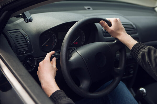 Close-up of  male hand on steering wheel in car