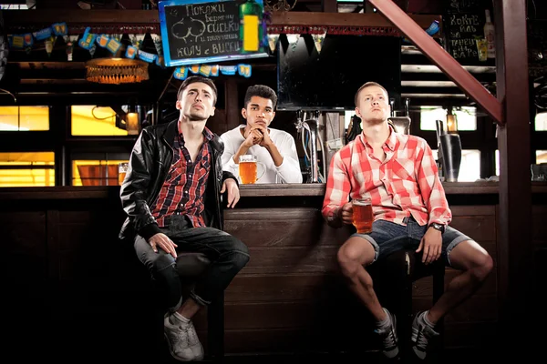 Tittar på Tv i baren. män dricker öl sitter bar — Stockfoto