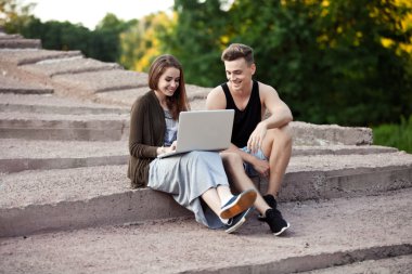 dizüstü bilgisayar ile bir yolda oturup sevgi dolu genç Çift