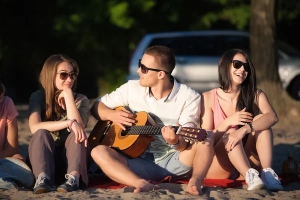 Skupina přátel, relaxační na písku na pláži s kytarou — Stock fotografie