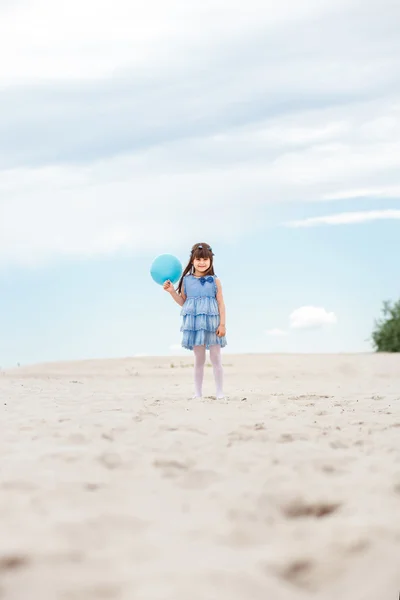 Kleines Mädchen spielt mit Luftballons am Strand — Stockfoto