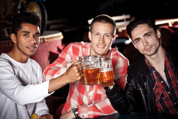 Счастливые друзья звонят с кружками пива в пабе, улыбаются . — стоковое фото