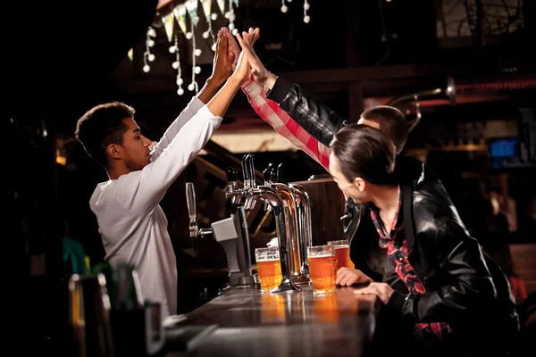 Amigos felizes clinking com canecas de cerveja no pub, sorrindo . — Fotografia de Stock