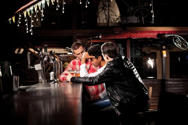 Amigos bebem cerveja e passam tempo juntos em um bar . — Fotografia de Stock