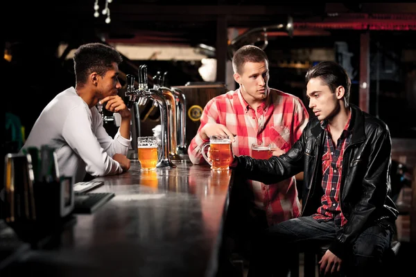 Amigos bebem cerveja e passam tempo juntos em um bar . — Fotografia de Stock