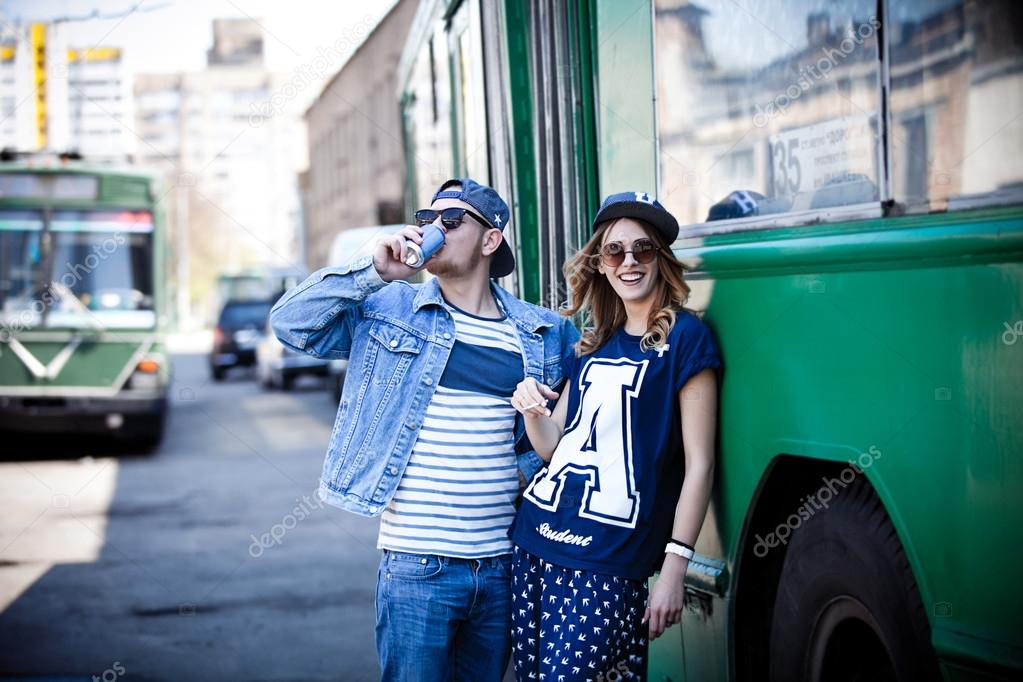 stylish couple with drinks near transport, bus, retro