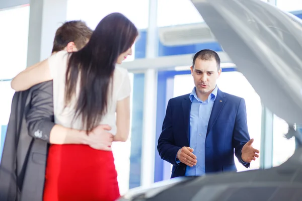 Venditore di auto dando la chiave della nuova auto per i giovani proprietari — Foto Stock