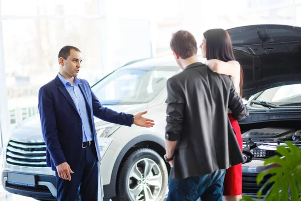 Car salesman giving key of  new car to  young  owners — Stock Photo, Image