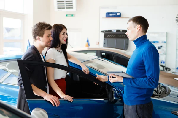 Venditore di auto dando la chiave della nuova auto per i giovani proprietari — Foto Stock