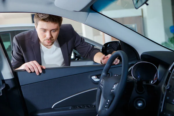 Uomo guardando la nuova auto nello showroom — Foto Stock