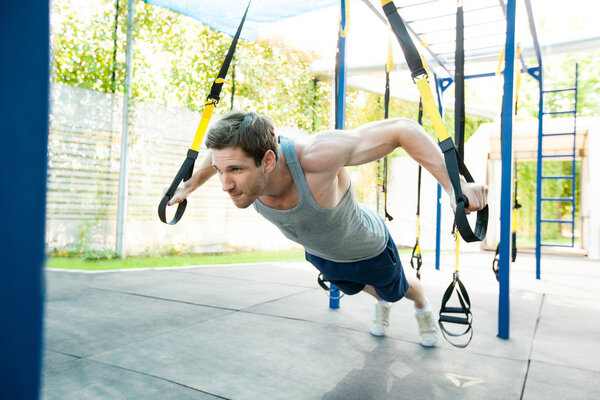 Man during workout with suspension straps on the street