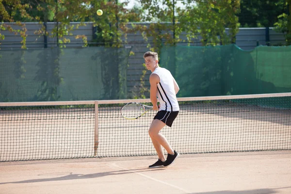 Young man play tennis outdoor on orange  court — Stock Photo, Image