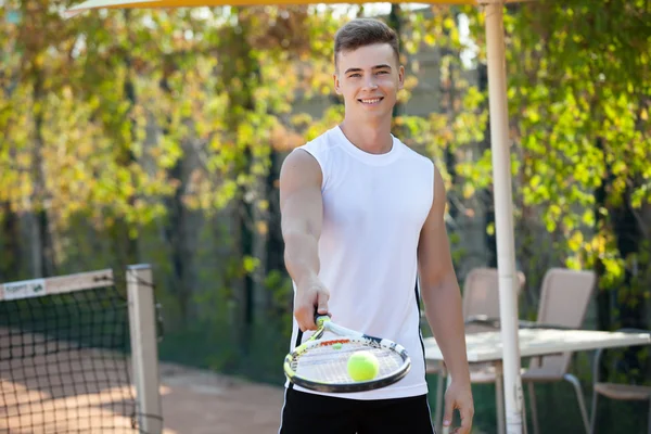 Молодий чоловік грає в теніс на відкритому повітрі на помаранчевому дворі — стокове фото