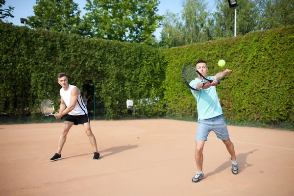 Mixed doubles player hitting tennis ball with partner — Stock Photo, Image