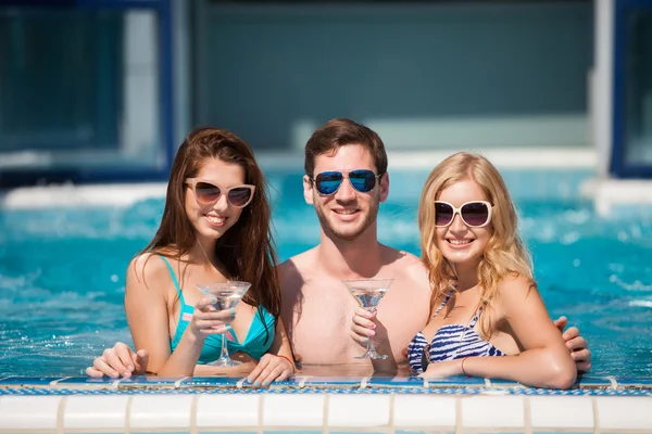 Chico coqueteando con dos mujeres en la piscina, beber — Foto de Stock