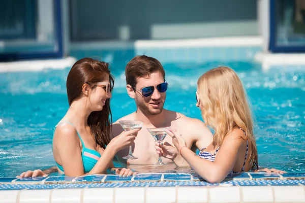 Chico coqueteando con dos mujeres en la piscina, beber — Foto de Stock