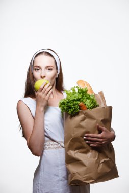 Elinde sebzeli alışveriş torbası tutan genç bir kadın.