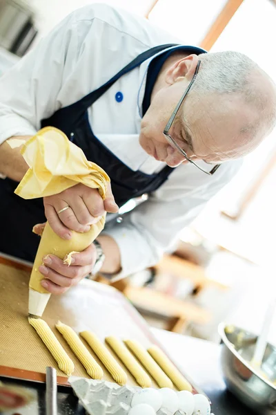 Il fornaio prepara una torta ed eclairs — Foto Stock