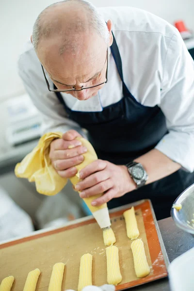 Il fornaio prepara una torta ed eclairs — Foto Stock