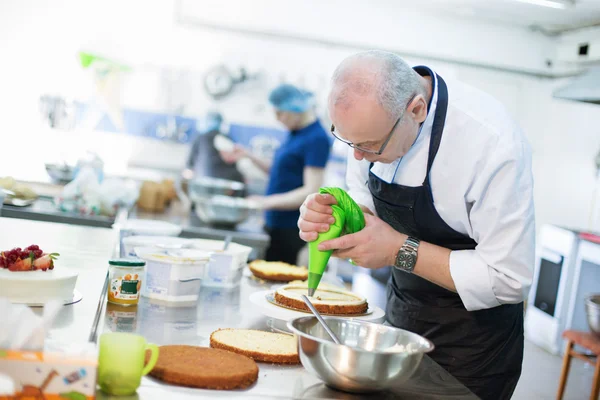 Il fornaio prepara una torta ed eclairs — Foto Stock