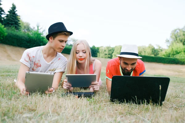 Technologie en mensen concept - groep vrienden met tablet pc-computers, smartphone zitten in park — Stockfoto