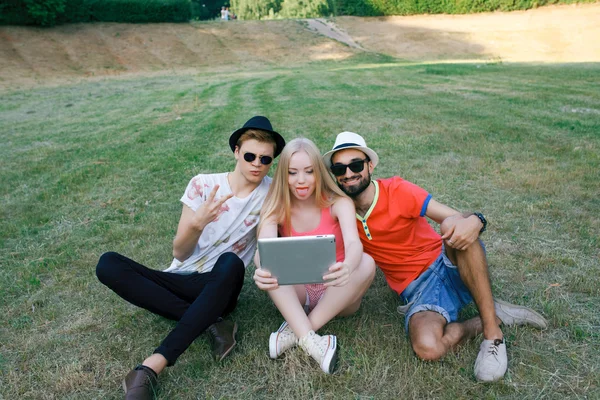 Technology and people concept - group  friends with tablet pc computers , smartphone sitting  in park — Stock Photo, Image