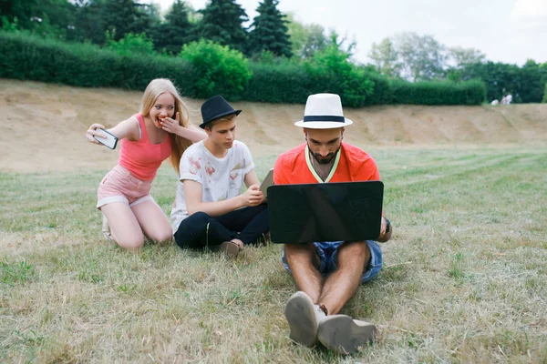 Teknik och människor koncept - grupp vänner med tablet pc-datorer, smartphone sitter i park — Stockfoto