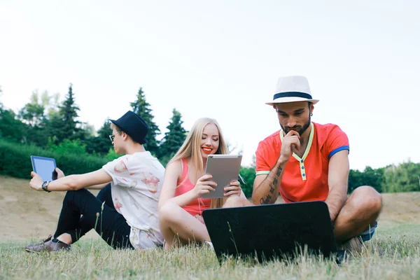 Teknik och människor koncept - grupp vänner med tablet pc-datorer, smartphone sitter i park — Stockfoto