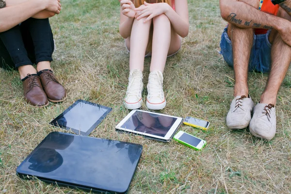 La tecnología y el concepto de personas - grupo de amigos con tabletas PC, teléfono inteligente sentado en el parque — Foto de Stock