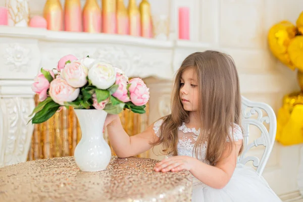 Little girl looks at a bouquet. — Stock Photo, Image