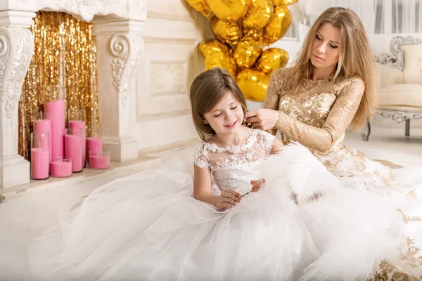 Madre pettinando figlia. Seduto sul pavimento con un bel vestito bianco . — Foto Stock