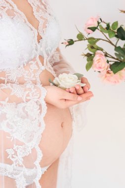 Bir çiçek tutan hamile kadın. Karınlarını portre.