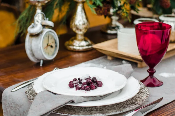 Тарелка с малиной в снегу на столе. красный бокал вина — стоковое фото