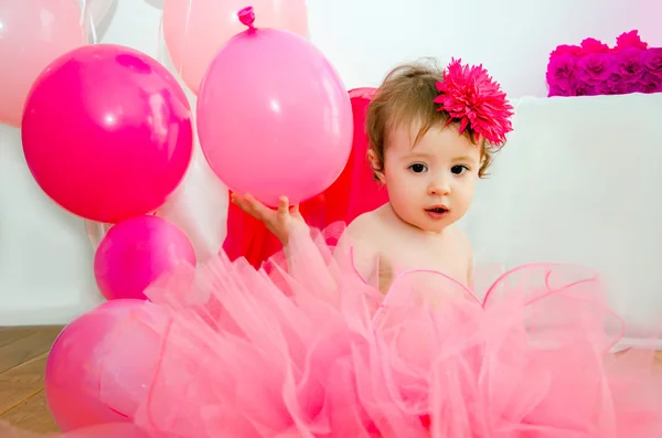 First birthday.Baby in fluffy pink skirt, with balloons and a big Digits 1 — Stock Photo, Image