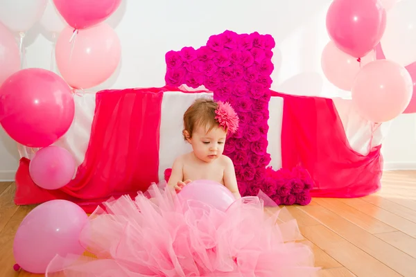 First birthday.Baby in fluffy pink skirt, with balloons and a big Digits 1 — Stock Photo, Image
