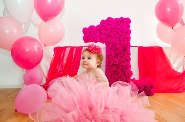 First birthday.Baby in fluffy pink skirt, with balloons and a big Digits 1 — Stock Photo, Image