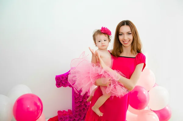 Mother holding a baby in her arms. Little girl in a pink skirt. — Stock Photo, Image