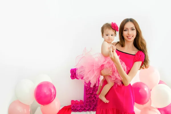 Madre che tiene un bambino tra le braccia. Ragazzina in gonna rosa . — Foto Stock