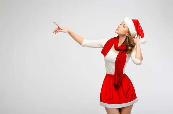 Christmas Santa hat isolerad kvinna porträtt. Ser åt sidan på en grå bakgrund. Flicka i vita och röda kläder — Stockfoto