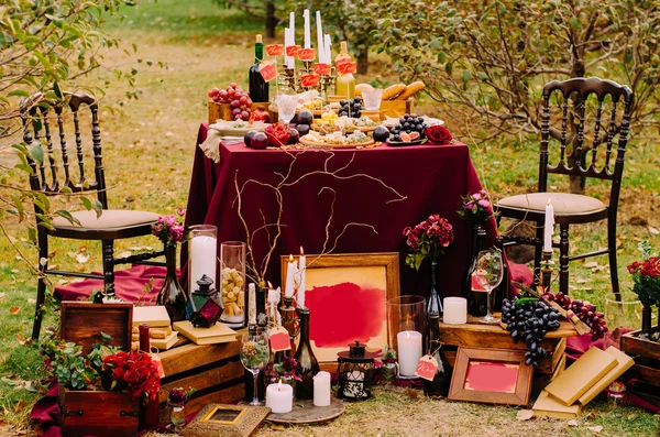 Свадебный стол с лечением.Стол и два стула с декором и едой на зеленой лужайке в парке . — стоковое фото