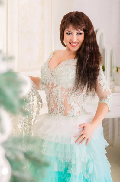 Hermosa chica sonriendo en vestido de novia de menta, de pie junto a la chimenea cerca de un árbol de Navidad . —  Fotos de Stock