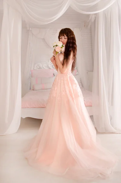 Schöne junge Braut in einem Pfirsichkleid. das sanfte helle Schlafzimmer. Hochzeit in rosa. — Stockfoto