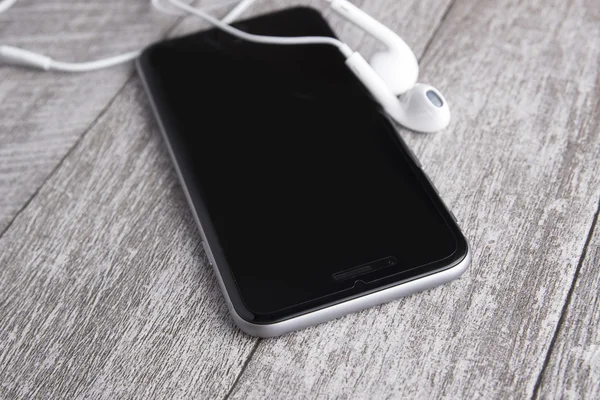 akıllı telefon ve kulaklık üzerinde ahşap masa