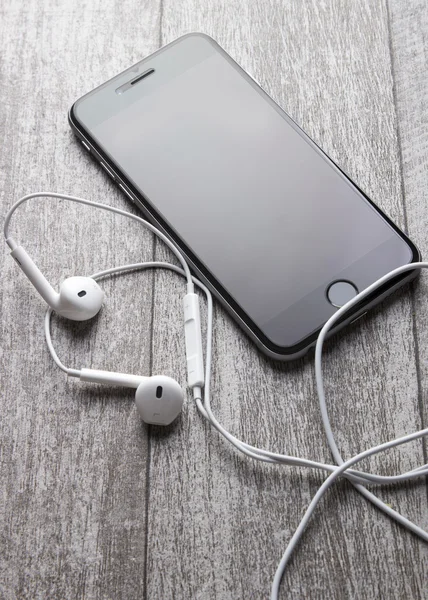 Smartphone e fones de ouvido na mesa de madeira — Fotografia de Stock